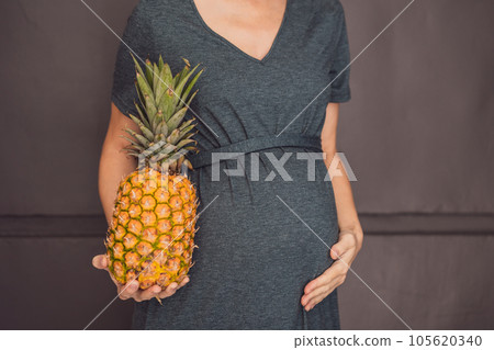 A pregnant woman's belly, beautifully showcasing the size of her baby, likened to a pineapple. Explore the potential benefits and harms of pineapple during pregnancy and childbirth 105620340