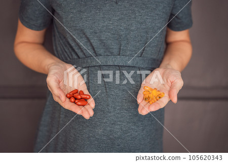 A happy and expectant mother holding omega 3 capsules, making a smart choice for her and her baby's health during pregnancy 105620343