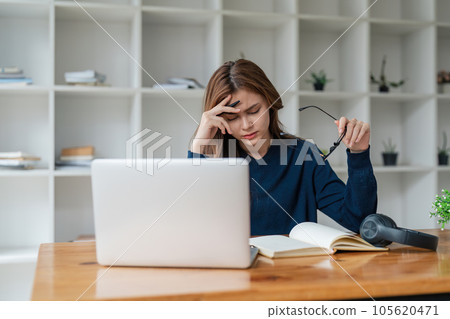 Tired asian woman bored with of laptop sad and frustrated about distance learning or online education sits at desk at home 105620471