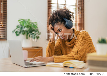 Tired curly African American woman bored with of laptop sad and frustrated about distance learning or online education sits at desk at home Tired curly African American woman bored with of laptop sad and frustrated about distance learning or online education sits at desk at home 105620538