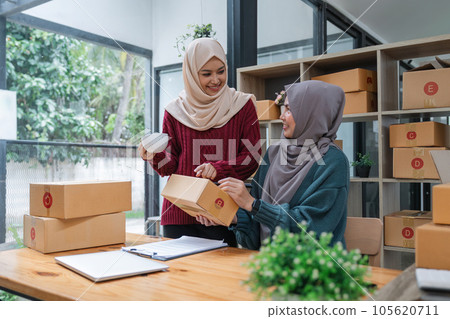 Muslim two woman freelancer sme business online shopping working on laptop computer and checklist order box at home Business online shipping and delivery concept 105620711