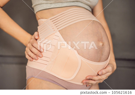 A pregnant woman feeling secure and supported, wearing a bandage designed for pregnancy to provide gentle support and comfort A pregnant woman feeling secure and supported, wearing a bandage designed for pregnancy to provide gentle support and comfort 105621616