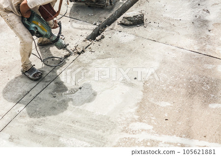 Construction worker using jackhammer drilling concrete surface 105621881