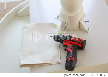 Cordless screwdriver on wood table assembly furniture concept Cordless screwdriver on wood table assembly furniture concept 105621897