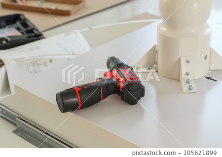 Cordless screwdriver on wood table assembly furniture concept Cordless screwdriver on wood table assembly furniture concept 105621899