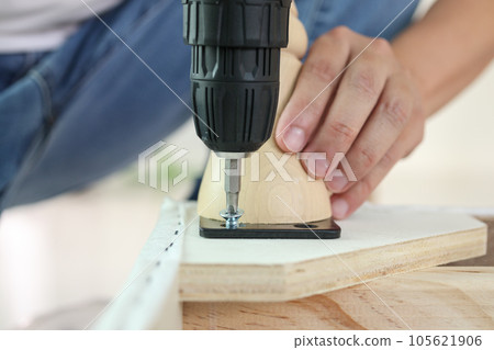 man assembling sofa furniture at home using cordless screwdriver man assembling sofa furniture at home using cordless screwdriver 105621906