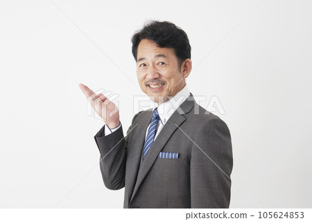 Middle-aged businessman pointing to the left with his palm White background Middle-aged businessman pointing to the left with his palm White background 105624853