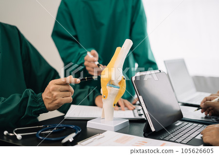 serious doctors team are analyzing fracture knee model showing the process of osteoarthritis patients and knee arthroplasty. serious doctors team are analyzing fracture knee model showing the process of osteoarthritis patients and knee arthroplasty. 105626605