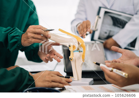serious doctors team are analyzing fracture knee model showing the process of osteoarthritis patients and knee arthroplasty. serious doctors team are analyzing fracture knee model showing the process of osteoarthritis patients and knee arthroplasty. 105626606