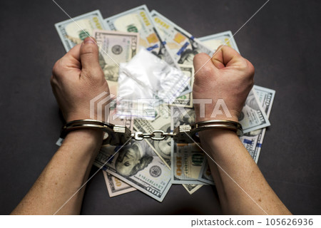 Man in handcuffs with money and drugs on dark background. Man in handcuffs with money and drugs on dark background. 105626936