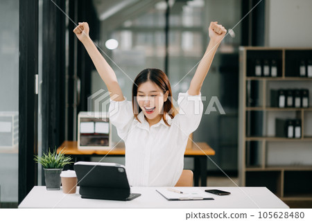 Asian business woman are delighted and happy with the work they do on their tablet, laptop and taking notes at office. 105628480