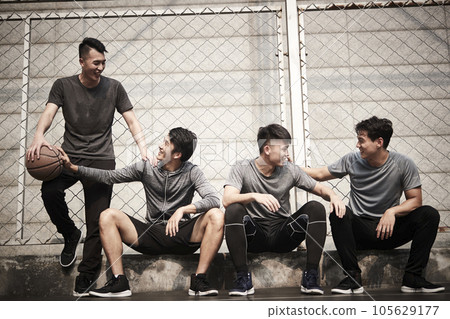 group of four asian young adult men resting relaxing talking chatting on outdoor basketball court group of four asian young adult men resting relaxing talking chatting on outdoor basketball court 105629177