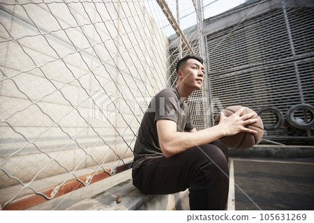 asian young adult man basketball player sitting resting at courtside asian young adult man basketball player sitting resting at courtside 105631269