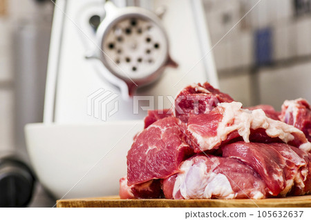Meat grinder with fresh meat on a cutting board in kitchen interior 105632637