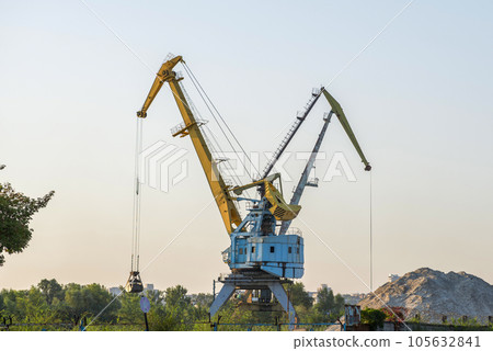 Harbour cranes are loading sand and gravel on a barge. Harbour cranes are loading sand and gravel on a barge. 105632841