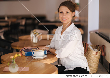 Beautiful female sits in cafe and read the book. Woman spend time after work Beautiful female sits in cafe and read the book. Woman spend time after work 105634393