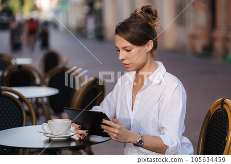 Portrait of attractive female freelancer using tablet in cafe on terrace Portrait of attractive female freelancer using tablet in cafe on terrace 105634459