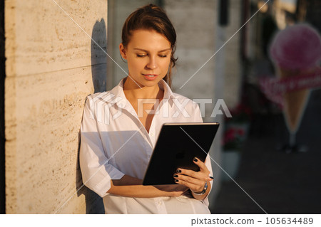 Portrait of woman using tablet outdoors. Female working on digital tablet 105634489