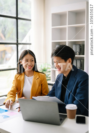 Two  Asian business  man and woman workers talking on the smartphone and using laptop Professionals in Teamwork  Finance, Marketing, and Success 105635017