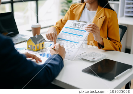 Buying a home or insurance deal, an insurance agent pointing a pen to those interested in renting a house, a contract, signing an Home buying agreement in modern office. Buying a home or insurance deal, an insurance agent pointing a pen to those interested in renting a house, a contract, signing an Home buying agreement in modern office. 105635068