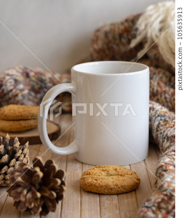 White coffee mug on wooden table near pine cones, cookies and sweater, winter mockup White coffee mug on wooden table near pine cones, cookies and sweater, winter mockup 105635913