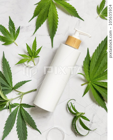 White One pump bottle near green cannabis leaves on marble top view. Cosmetic Mockup White One pump bottle near green cannabis leaves on marble top view. Cosmetic Mockup 105635914