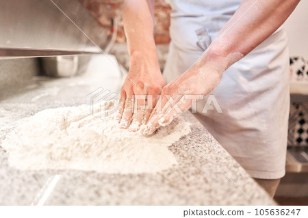 The chef prepare pizza. Raw pizza ready to bake. Cook in a apron in the kitchen Rolls out pizza dough. boxes for food delivery on background. 105636247