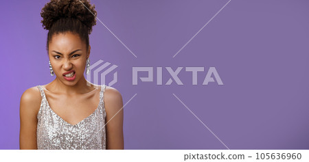 Displeased arrogant african-american woman in silver glittering dress cringing dislike awful smell standing bothered displeased look disgusted frowning standing reluctant blue background Displeased arrogant african-american woman in silver glittering dress cringing dislike awful smell standing bothered displeased look disgusted frowning standing reluctant blue background 105636960