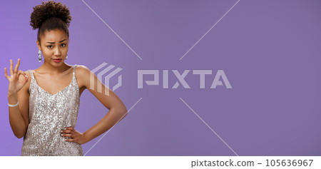 Doubtful suspicious clever african-american young woman in silver dress deal cover friend show okay ok confirmation gesture smirking frowning unsure questioned express disbelief hesitation 105636967