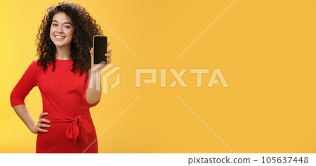 Girl brag with new phone she got on christmas feeling delighted holding mobile device in hand showing smartphone screena t camera, smiling broadly with uplifted mood over yellow background Girl brag with new phone she got on christmas feeling delighted holding mobile device in hand showing smartphone screena t camera, smiling broadly with uplifted mood over yellow background 105637448