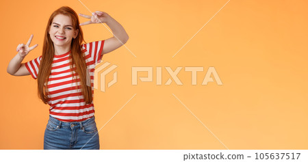 Friendly upbeat good-looking redhead woman rejoicing, feel happy, enjoy summetime, take first photo vacation, send coworkers summer shot, make peace victory signs, smiling broadly orange background 105637517