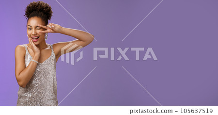 Sassy elegant confident african-american woman in stylish silver dress touch cheek show peace victory gesture feel lucky self-assured wear luxurious dress attend wealthy party, blue background 105637519