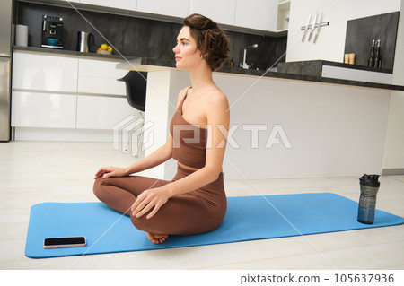 Fit healthy young woman doing pilates yoga exercise fitness training workout at home interior standing in warrior pose. Physical activity for body and mind relaxation, healthy lifestyle concept 105637936
