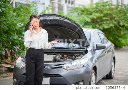 female motorist is calling an insurance or recovery service officer for assistance related to a car accident. 105638544