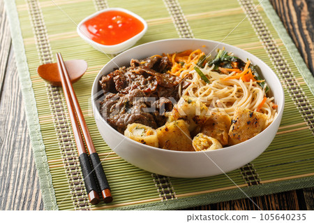 Vietnamese beef noodles salad bun bo xao is filled in fresh herb, savory beef, vegetables and fried spring rolls closeup. Horizontal 105640235