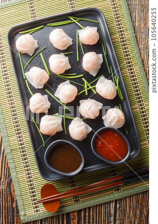 Traditional Asian Prawn or shrimp dumplings hakau, ha kauw or har gow served with sauce. Vertical top view 105640255