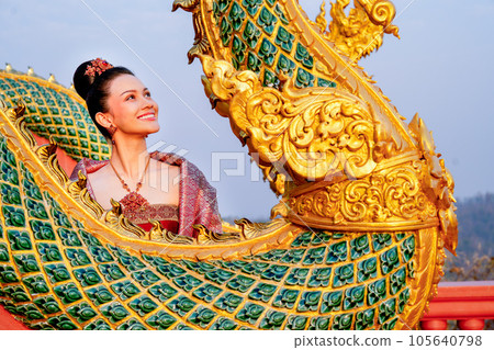 Close up beautiful Asian woman with Thai traditional dress stand behide the naga  sculpture 105640798