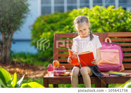 girl is having lunch sitting next to the school 105641736