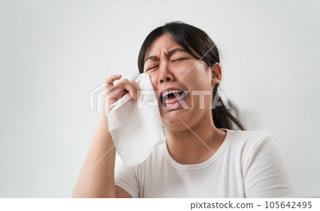 Portrait of a Sad Asian woman crying wipes her tears with a tissue paper towel. 105642495