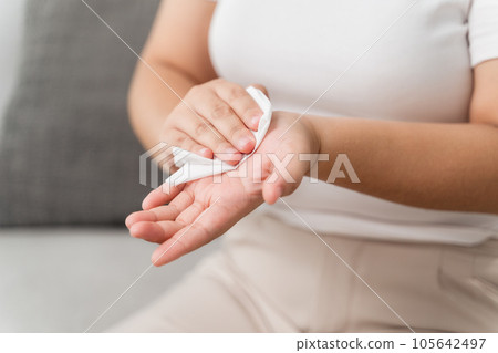 Woman wipes cleaning her hand with a tissue paper towel. Healthcare and medical concept. Woman wipes cleaning her hand with a tissue paper towel. Healthcare and medical concept. 105642497