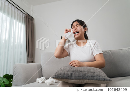 Portrait of a Sad Asian woman crying wipes her tears with a tissue paper towel. Portrait of a Sad Asian woman crying wipes her tears with a tissue paper towel. 105642499