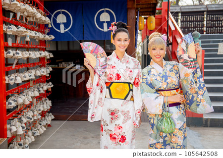 Portrait of Asian women wear japanese style dress with hold multicolor fan and stand in front shop 105642508
