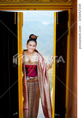 Beautiful Asian woman wear Thai traditional dress stand in area of ancient door of building temple 105642509