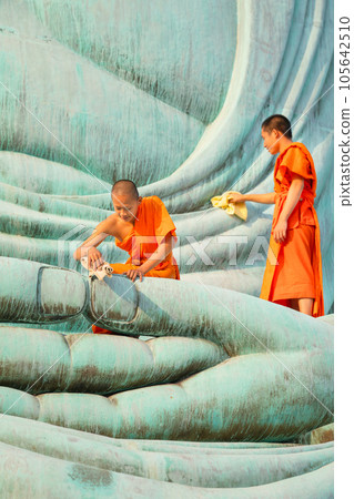 Vertical image of two young Asian monk stay with other monk on green big buddha statue to clean 105642510