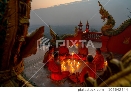 Side view group of young and senior monk sit in a circle with several lighting candle surround 105642544