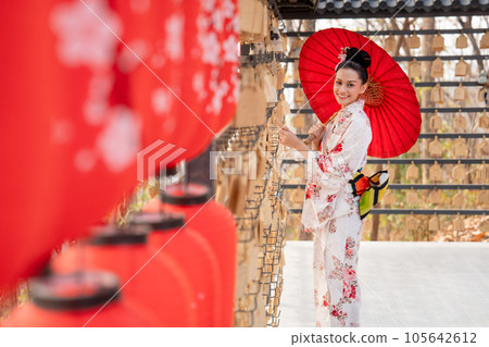 Portrait of pretty young woman wear japanese style dress and hold red umbrella also look at camera 105642612