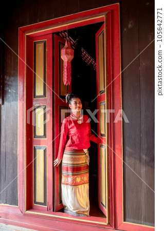 Vertical image of young Asian woman with Thai Lanna traditional dress stand at door with red color 105642771