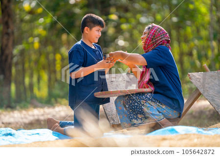 Asian boy bring drinking water and give to woman and she look happy during process of rice prepare 105642872