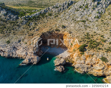 Top view of a beautiful sea harbor. Lagoon with dark blue water. Waves near rocky coast and boat Top view of a beautiful sea harbor. Lagoon with dark blue water. Waves near rocky coast and boat 105643214