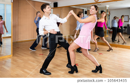 Couple of young dancers rehearsing ballroom dances in dance studio Couple of young dancers rehearsing ballroom dances in dance studio 105643435